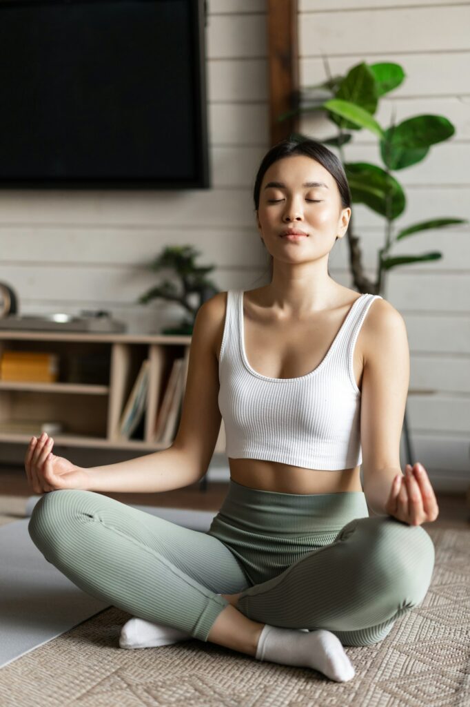 Mindfulness and meditation concept. Young asian woman doing workout at home, yoga meditation in