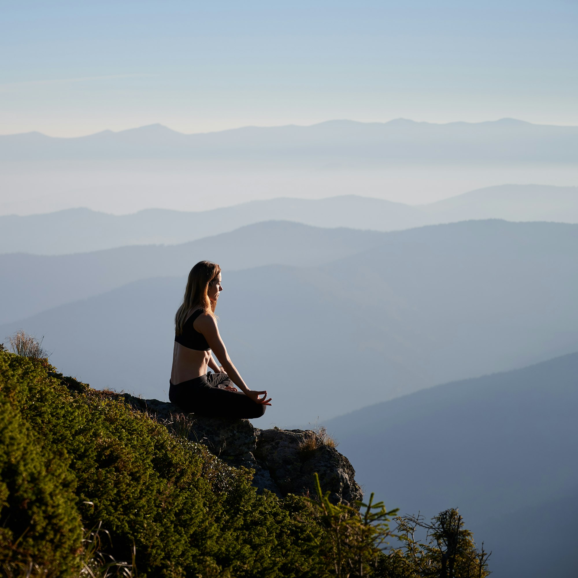 About me 4 Sporty young woman meditating in mountains.