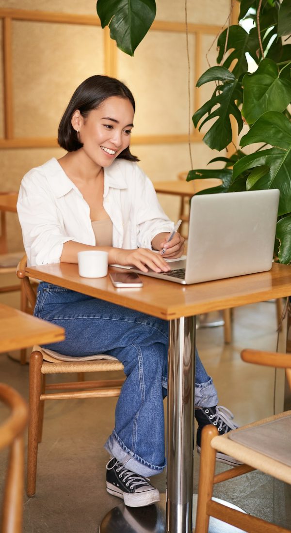 Stylish businesswoman with laptop, sitting in cafe and working on computer, managing business and